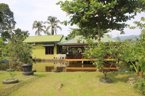 a yellow house with a deck in a yard at AMBOW Homestay Jungle Trekking & Village Tour in Bukit Lawang