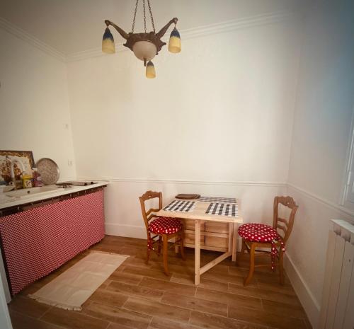 een keuken met een tafel en stoelen en een kroonluchter bij Le cottage des artistes in Champigny-sur-Marne
