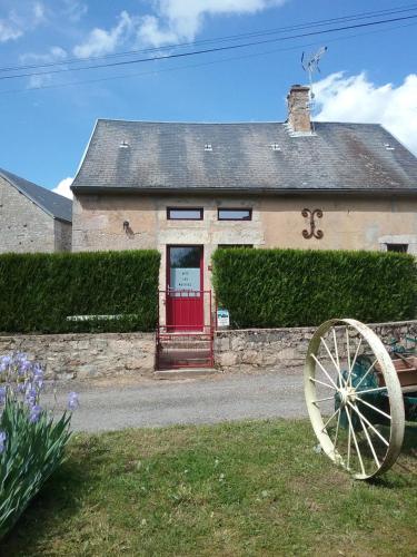 a house with a red door and a wooden wheel at Les petites Fourches in Saint-Brisson