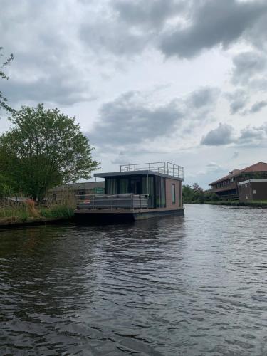 a house boat parked on the side of a river at Houseboot solcamastraat 24 c in Suameer