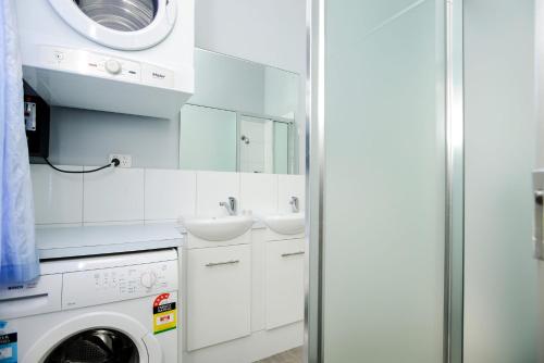a white bathroom with a washing machine and a sink at Beachfront Bliss - Wi-fi Bbq Group House in Victor Harbor