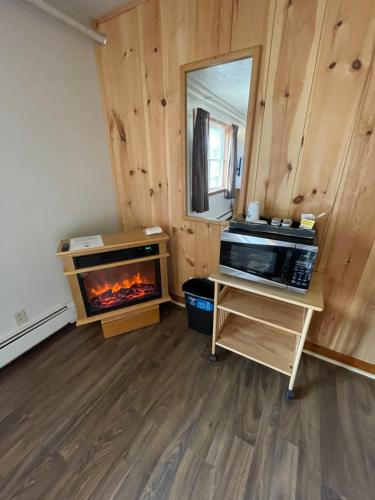 a living room with a fireplace and a microwave at Spillover Motel and Inn in Stratton