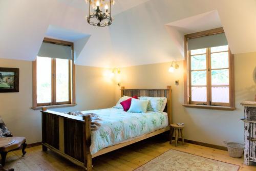 a bedroom with a bed and two windows at Adelaide Hills Camellia Cottage Wifi in Crafers