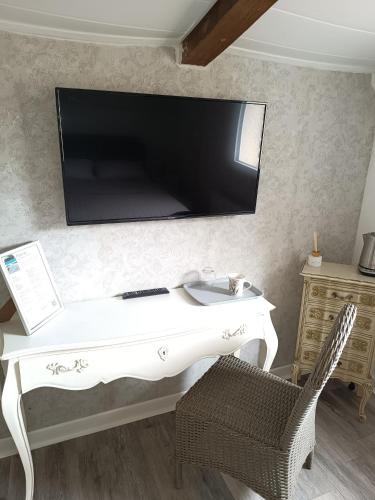 - un bureau blanc avec une télévision murale dans l'établissement La Capitelle , Chambre double indépendante avec piscine, à Deaux