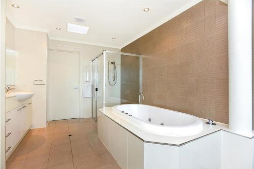a white bathroom with a tub and a sink at Gallery Resort Style Penthouse No 13 in Victor Harbor