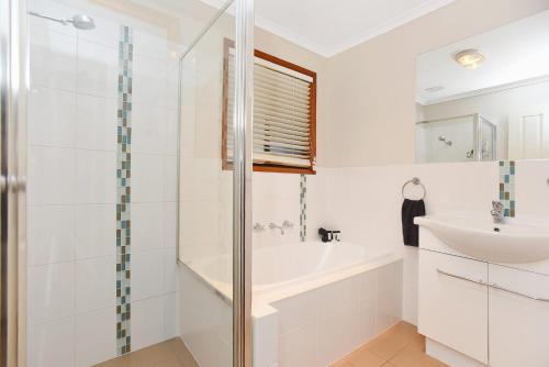 a bathroom with a tub and a sink and a shower at Goolwa Blue Escape - Beach Spacious Wi-fi in Goolwa