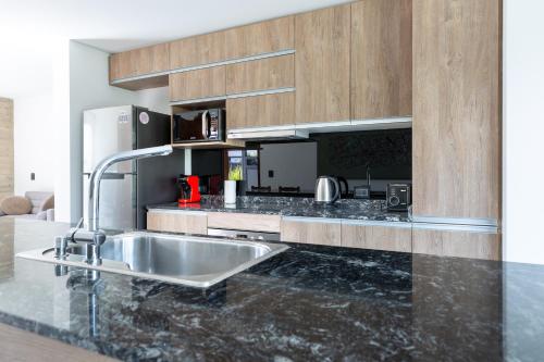 eine Küche mit einer Spüle aus Edelstahl und Holzschränken in der Unterkunft The Acacia Village in Ciudad Lujan de Cuyo