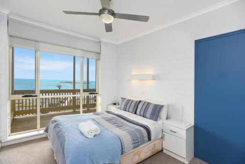 a bedroom with a bed and a balcony with the ocean at 'The Dolphins 7' - Beachfront View To Remember in Port Elliot