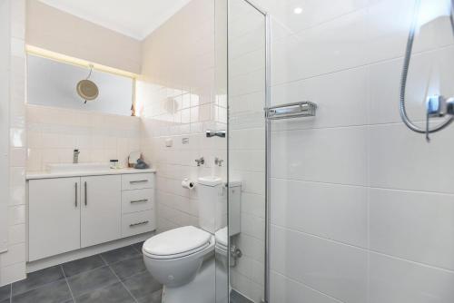 a white bathroom with a toilet and a shower at 'The Dolphins 7' - Beachfront View To Remember in Port Elliot