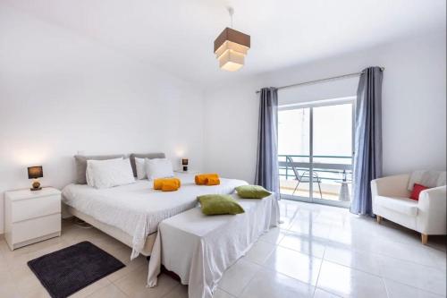 a white bedroom with two beds and a chair at Casa Cláudia - Centro Histórico in Lagos