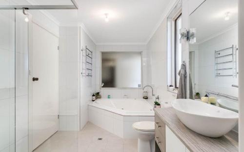 baño blanco con bañera, aseo y lavamanos en Glass House By The Ocean Wi-fi, en Middleton
