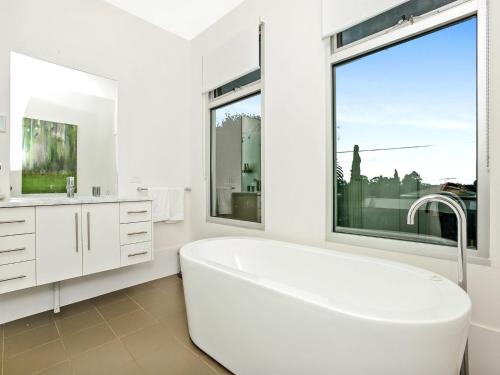 a white bathroom with a tub and a large window at Muse On The Murray Pet-friendly in Wellington