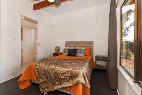 ein Schlafzimmer mit einem Bett mit einer orangefarbenen Decke in der Unterkunft Riverglades Murray Bridge in Murray Bridge