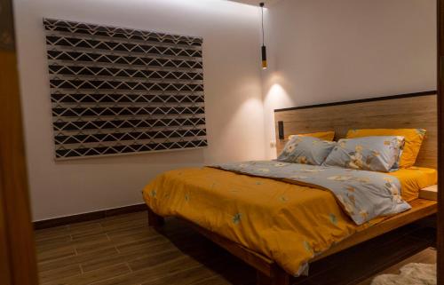 sypialnia z łóżkiem z żółtą pościelą i poduszkami w obiekcie Oasis Appart Benin w mieście Kotonu