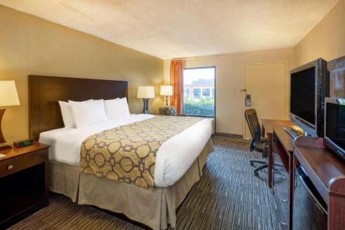 a hotel room with a bed and a desk and a television at Baymont by Wyndham Columbus GA in Columbus