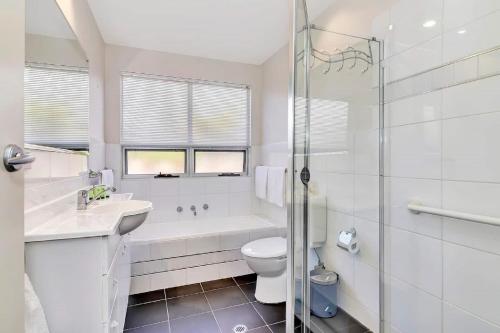 a white bathroom with a tub and a toilet and a sink at The Darling Of Marina - A Hilltop And Sea Getaway in Wirrina Cove