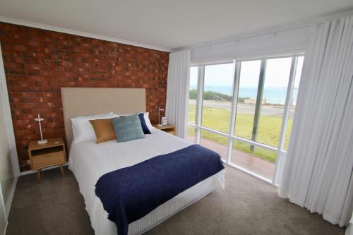 a bedroom with a bed and a large window at Southern Sands' Beachfront Apartment in Port Elliot