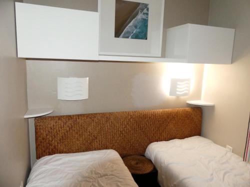 Cette petite chambre comprend 2 lits et des armoires blanches. dans l'établissement Appart 4 pers av balcon-parking gratuit-piscine int chauffée-serviettes et linge de lit compris, à Le Touquet-Paris-Plage