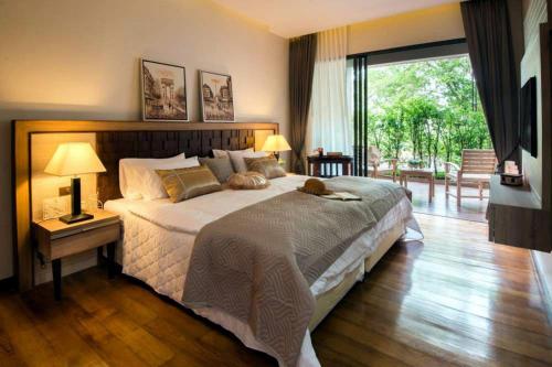 una camera da letto con un grande letto con un gatto steso sopra di Rimnaam Klangchan Hotel - SHA Plus a Chanthaburi