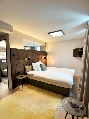 ein Schlafzimmer mit einem großen Bett und einem Spiegel in der Unterkunft Boutique Hotel Sonne Seuzach in Winterthur