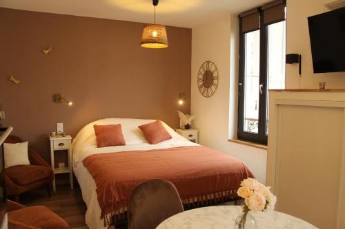 - une chambre avec un lit, une table et une télévision dans l'établissement L'Embellie, à Aix-les-Bains