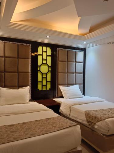 a bedroom with two beds and a stained glass window at Aldar Hotel in Jazan