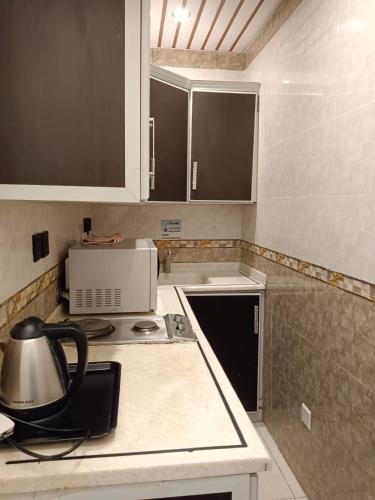 a kitchen with a stove and a tea kettle on a counter at Aldar Hotel in Jazan