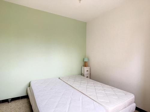 une chambre avec un lit blanc et un mur vert dans l'établissement Charmant 2 pièces rénové proche plage avec loggia vitrée, TV, local vélos et parking - FR-1-715-66, à Mauguio