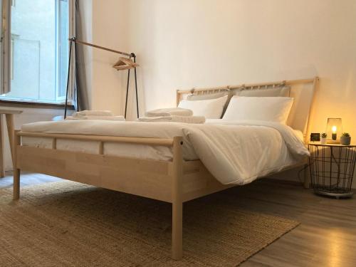 uma cama com lençóis brancos e almofadas num quarto em No Name - Via dell'Istria 12 em Trieste
