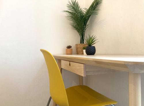 uma cadeira amarela ao lado de uma secretária com uma planta em No Name - Via dell'Istria 12 em Trieste