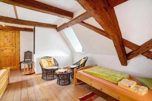 Cette chambre mansardée comprend un lit et des chaises. dans l'établissement Ferienwohnungen 'am Waldrand', à Hartmannsbach