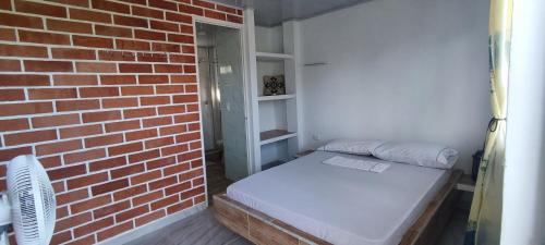 Habitación pequeña con pared de ladrillo y cama en Cabaña la Gloria, en San Onofre