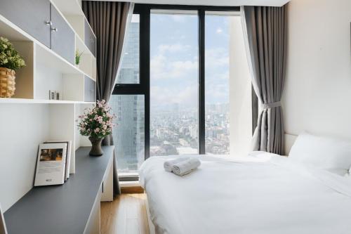 ein Schlafzimmer mit einem weißen Bett und einem großen Fenster in der Unterkunft Lynn Housing- Vinhomes Metropolis- LUX. Apartment system in Hanoi