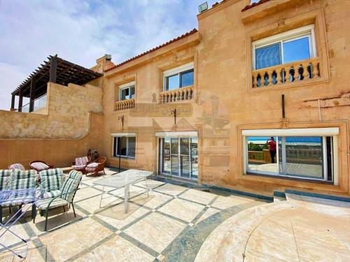 uma casa com um pátio com uma mesa e cadeiras em Villa with a charming view, sea view, Marina em El Alamein