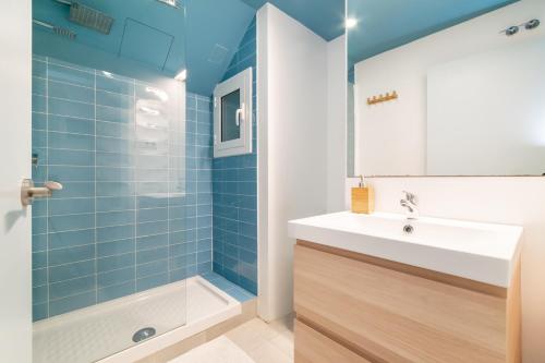 ein Badezimmer mit einem Waschbecken und einer Dusche mit blauen Fliesen in der Unterkunft Apartment Pontevedra 20m from the beach in Barcelona