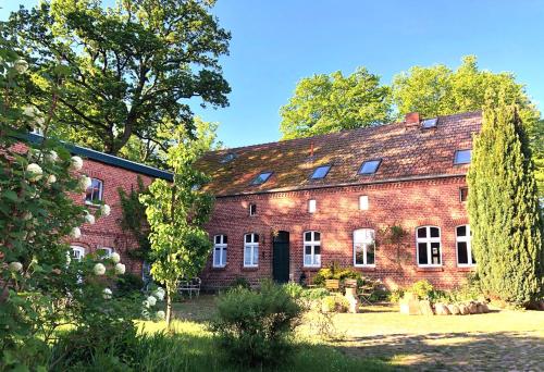 un antiguo edificio de ladrillo rojo con ventanas y árboles en Romantische Ferienwohnung Unter den Linden en Buchholz