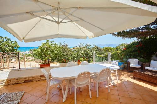 uma mesa branca e cadeiras sob um guarda-sol num pátio em Villa Azzurra em Castellammare del Golfo