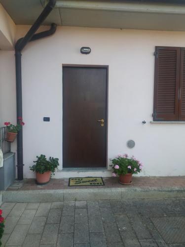 Una porta nera su un edificio bianco con due piante in vaso di Appartamento Sofia a Carbonara al Ticino