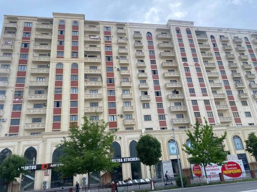 un gran edificio de apartamentos con muchas ventanas en una calle en Квартира 3-ух Комнатная в центре города, en Ferganá