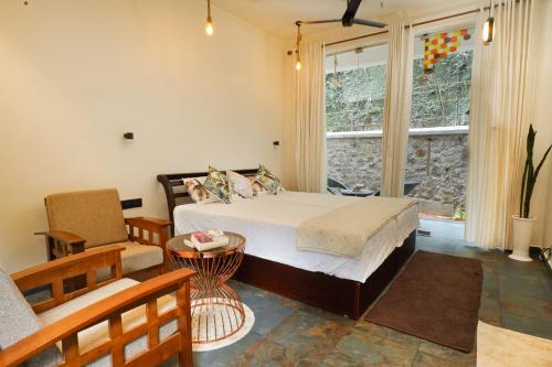 a bedroom with a bed and a couch and a window at Mickey Homestay in Thekkady