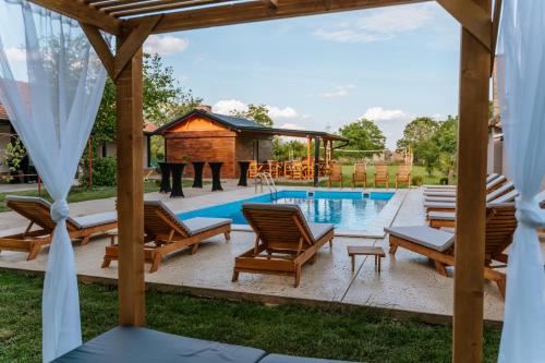 einen Pool im Hinterhof mit Stühlen und einem Pavillon in der Unterkunft B&B LUX Pavlovci in Pavlovci