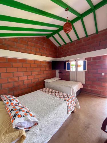 two beds in a room with a brick wall at Finca Hotel Isla del Encanto in Támesis