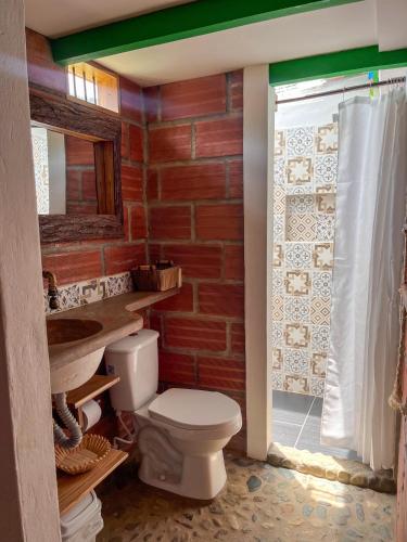 a bathroom with a toilet and a brick wall at Finca Hotel Isla del Encanto in Támesis