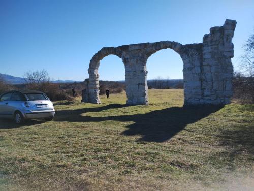 an old stone arch with a car parked in a field at Krka Ivan in Lozovac