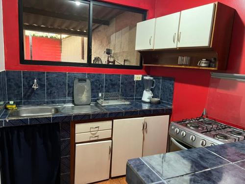 a kitchen with white cabinets and red walls at surf house in Puerto Baquerizo Moreno