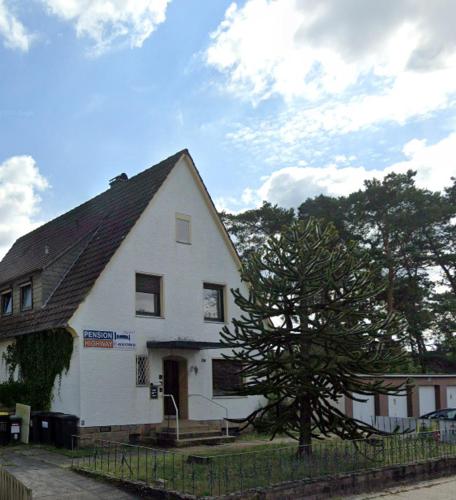 a white house with a tree in front of it at Pension Highway Bielefeld Senner Hellweg in Bielefeld
