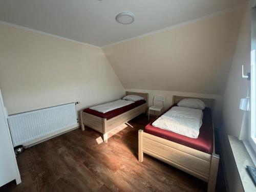 two beds in a small room with wooden floors at Pension Highway Bielefeld Senner Hellweg in Bielefeld