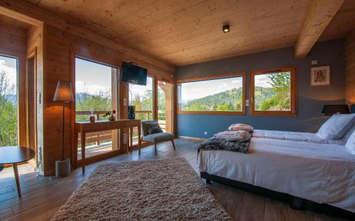 a bedroom with a bed and a desk and windows at Les Chalets de La Marcairie in Metzeral