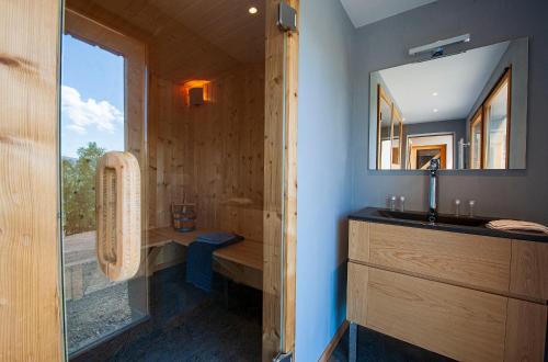 a bathroom with a shower with a sink and a mirror at Les Chalets de La Marcairie in Metzeral