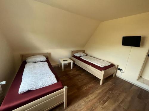 a room with two beds and a tv on the wall at Pension Highway Bielefeld Senner Hellweg in Bielefeld